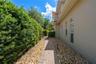 Paver walkway with river rock border and privacy hedge.