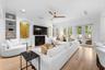 Built-in bookcases flanking the fireplace, French doors with lanai access, and light wood flooring.