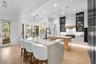 Island seating for four, matte black faucet, and under-cabinet lighting.
