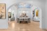View through the arched entry to the dining room, showing the mural ceiling and chandelier.