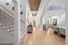 Foyer with light wood flooring, wood-inlay ceiling detail, staircase with iron balusters, and arched openings to the living spaces.