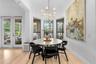 Casual dining area with French doors to the lanai, candle-style chandelier, and light wood flooring.