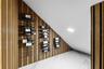 Wall-mounted wine racks on a vertical wood slat wall with recessed lighting.
