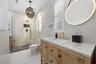Second Bathroom (upstairs) - Walk-in shower with black fixtures, wood vanity with stone top, and brass-framed round mirror.