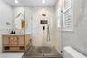 Second Bathroom (upstairs) - Glass-enclosed shower with three-dimensional tile, wall niche, and window with plantation shutters.