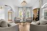 Sitting area with arched windows, plantation shutters, crown molding, and a crystal-style pendant fixture.