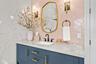 Vanity detail with brass-framed mirror, sconces, and matte black faucet.