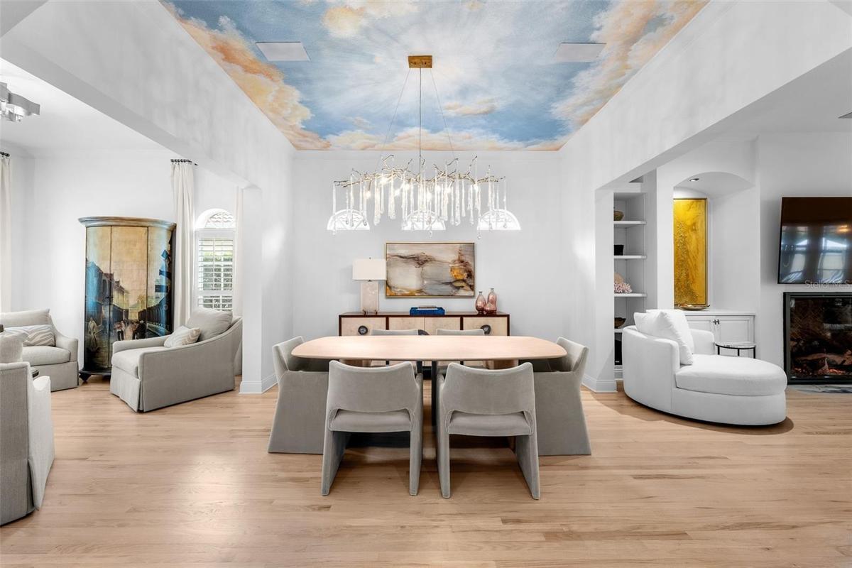 Sky ceiling mural, arched clerestory windows, and built-in cabinetry with open shelving.