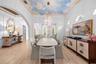 Formal dining space with a hand-painted sky ceiling mural, tiered chandelier, and built-in display shelving.