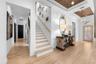 Wood-tread stairs with iron spindles, wall paneling, and a wood-inlay tray ceiling above the entry.
