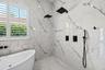 Dual black rain showerheads, wall niche, and marble-look wall tile.
