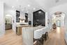 Two-tone cabinetry, waterfall-edge stone island with bar seating, pendant lighting, and arched openings to the foyer.