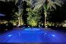 Resort Style Pool surrounded by lush tropical landscaping and dramatic evening lighting