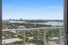 Expansive waterway and city skyline scenery from a high-rise balcony with glass railings