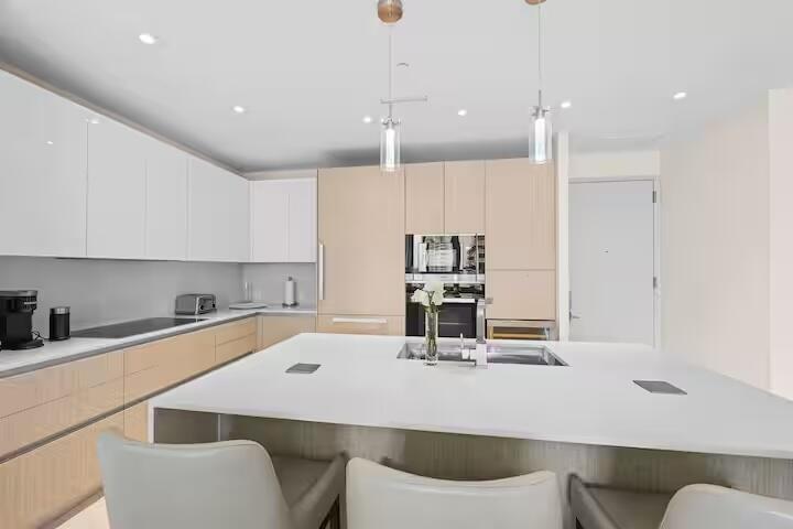Kitchen featuring an oversized island, integrated appliances, recessed lighting, pendant lighting, and two-tone cabinetry