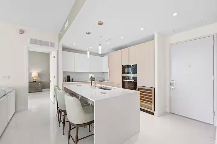 Sleek kitchen with a waterfall island, integrated stainless steel appliances, and a built-in wine cooler