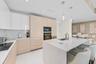 Sleek kitchen featuring a large island with integrated sink, contemporary recessed lighting, light wood-finish cabinetry, built-in oven, and a flat-su