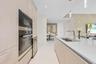 Integrated stainless steel appliances, wood-finish cabinetry, white countertop island with undermount sink, and recessed lighting