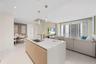 Modern kitchen island with integrated sink, pendant lighting, and light wood-finish cabinetry