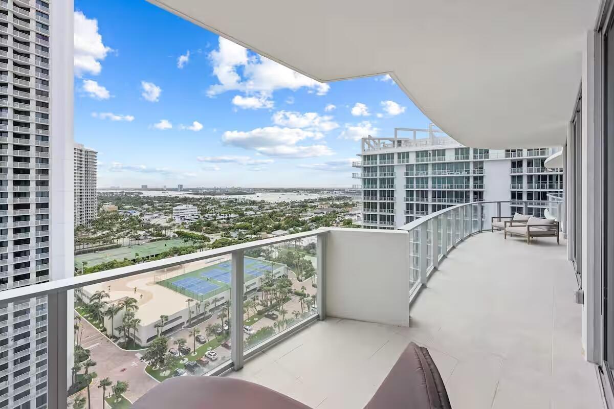 Expansive curved balcony featuring glass railing and tile flooring