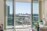 Sliding glass doors opening to a private balcony with glass railings, showcasing expansive water and city vistas