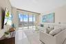 Expansive floor-to-ceiling windows, high ceilings, a wall-mounted television, polished tile flooring, and a built-in credenza