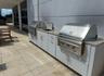 Outdoor kitchen featuring a built-in grill, integrated sink, and white cabinetry with stone countertops
