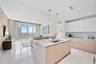 Open-concept living area with high ceilings, floor-to-ceiling windows, and white tile flooring