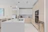 Modern kitchen featuring a waterfall island, integrated sink, pendant lighting, and stainless steel appliances