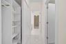 Hallway featuring white walls, light-toned flooring, built-in shelving, and a closet with a hanging rod