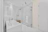 Freestanding soaking tub with floor-mounted fixtures, frameless glass shower enclosure, and white tile surround
