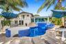 Backyard oasis featuring a curvilinear pool with blue mosaic tiling, integrated spa, and an elevated sundeck
