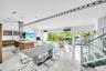 Open-concept living area with polished marble flooring, a modern kitchen island with wood-finish cabinetry, a stainless steel range hood, and a contem