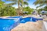 Multi-level swimming pool with blue mosaic tile accents, integrated spa, travertine paver decking, and lush tropical landscaping
