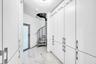 Custom built-in storage cabinetry, polished tile flooring, contemporary spiral staircase, and modern door with frosted glass