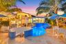 Curved swimming pool with blue tile accents, adjacent spa, integrated seating area, and multiple water features, surrounded by stone-finish paving