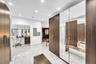 White marble-look tile flooring, recessed lighting, wood-finish cabinetry, full-height mirrored wardrobe doors, and modern wall-mounted light fixtures