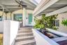 Covered entry with exposed beam ceiling, built-in koi pond with waterfall feature, and paver steps