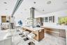 Open-concept kitchen featuring an expansive island, wood-finish cabinetry, integrated stainless steel appliances, and recessed lighting