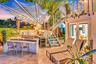 Outdoor kitchen with stainless steel grill, under-counter beverage cooler, and built-in bar seating