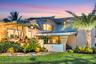 Modern exterior architecture with multiple rooflines, lush landscaping, exterior lighting, an expansive lawn, and a prominent palm tree