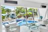 Expansive windows overlooking a pool with blue mosaic tile and a waterway