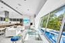 Open-concept living space with large format tile flooring, a contemporary kitchen featuring a stainless steel range hood, and extensive floor-to-ceili