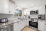 Crisp white cabinetry, stainless steel appliances, granite counters, and subway tile create a bright, fresh kitchen with plenty of workspace and stora