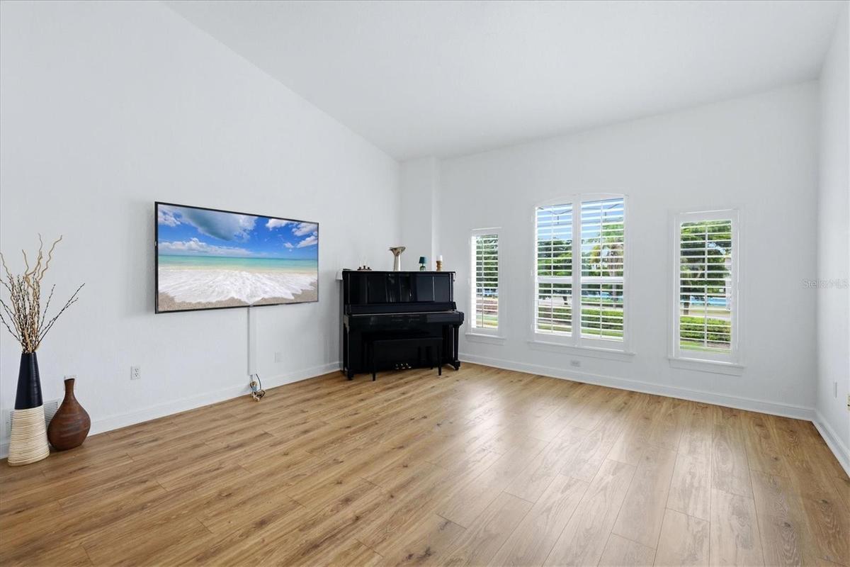 spacious family room with plantation shutters, vaulted ceilings, and items that convey