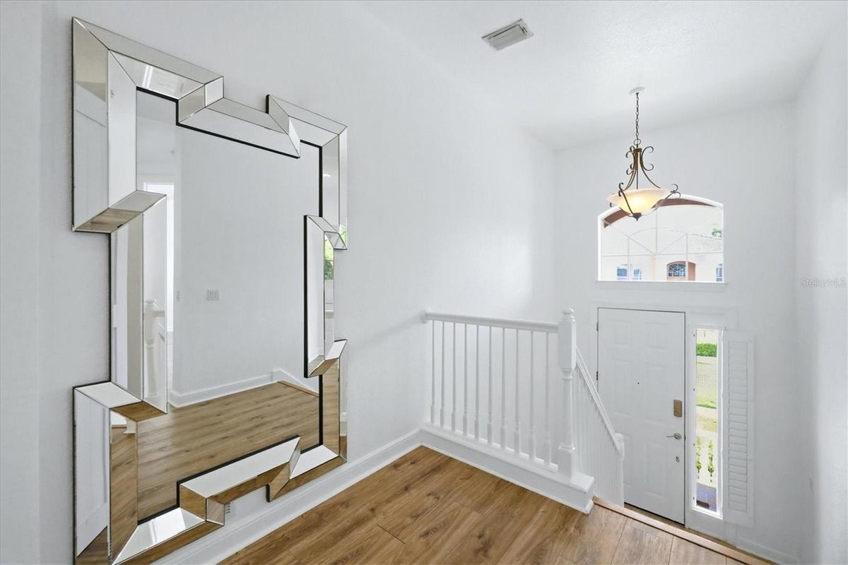 foyer, stairs lead up to main living area, and down to garage and storage closets