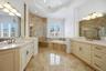master bathroom with large vanities, walk in shower, garden soaking tub, blonde cabinets and stone counters