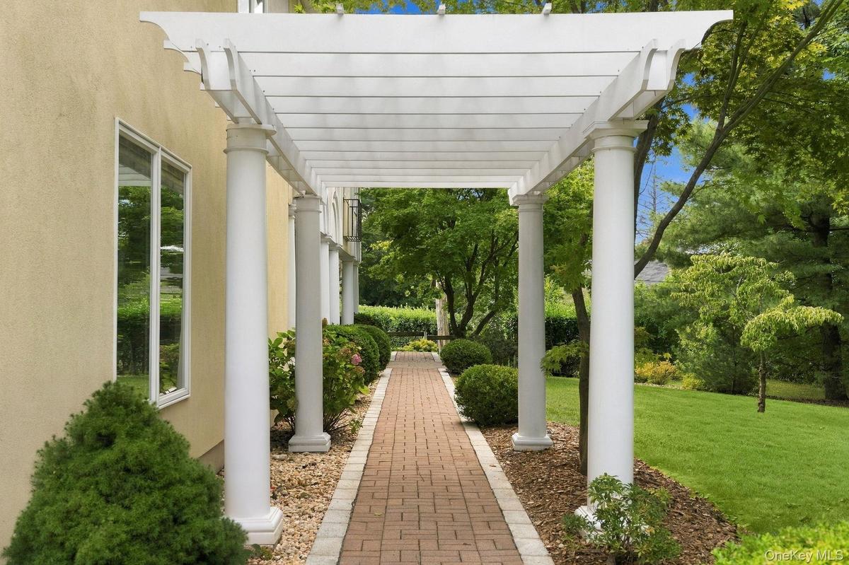 A gracious garden walkway leads beneath an impressive columned portico.