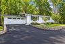 White siding exterior with a two-car garage, brand new asphalt driveway, and a stone retaining wall