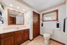 Additional bathroom view showcasing the spacious vanity, wood cabinetry, natural light, and convenient storage.
